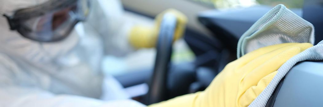 A man in a uniform wipes the interior of a car with a towel, close-up. Professional dry cleaning in a car service