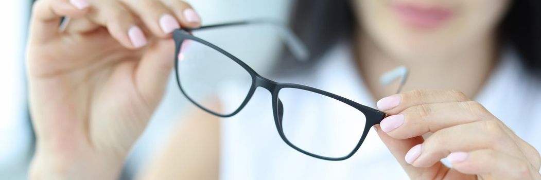 Woman holding stylish glasses for vision, close-up. Ophthalmologist selects frames, fashion accessories, optometrist