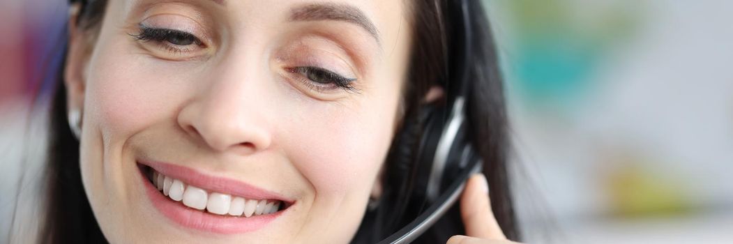 A woman in headset works in a call center, a smiling face close-up. Hotline, online consultation, telemarketing