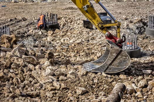 View of a part of single excavator arm with hydraulic Hoses and cylinder at a construction site. Close