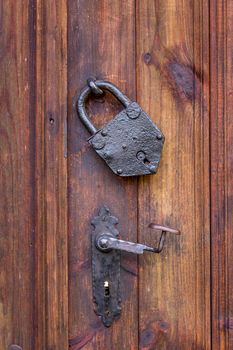 Door handle and a metal vintage padlock on the wooden door. True retro style. Close