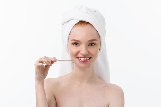 Portrait of young woman with toothbrush on grey background