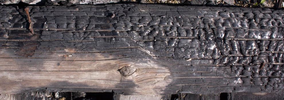 Black background. Burnt wooden Board texture. Burned scratched hardwood surface. Smoking wood plank background. Burned wooden grunge texture Space for text.