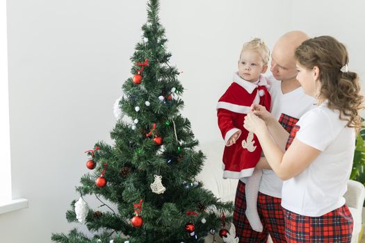 Baby child with hearing aid and cochlear implant having fun with parents in christmas room. Deaf and health