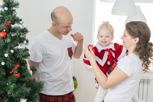 Baby child with hearing aid and cochlear implant having fun with parents in christmas room. Deaf and health