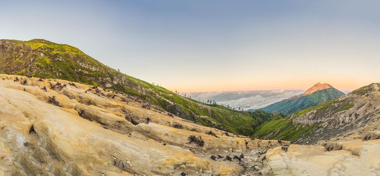 Panoramic shot of the Ijen volcano or Kawah Ijen on the Indonesian language. Famous volcano containing the biggest in the world acid lake and sulfur mining spot at the place where volcanic gasses come from the volcano.