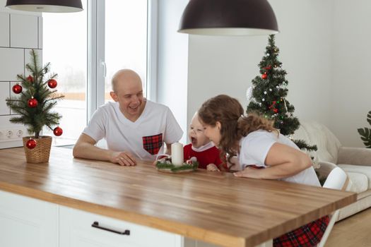 Baby child with hearing aid and cochlear implant having fun with parents in christmas room. Deaf and health