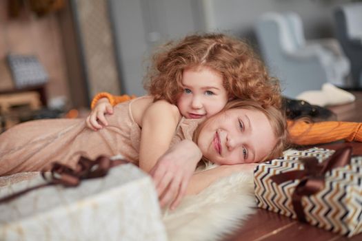 two pretty sisters are having fun in a cozy living room . the concept of Christmas