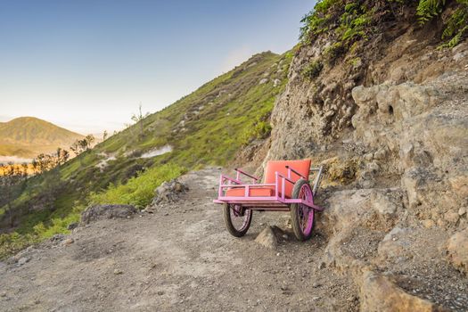 On a mountain road trecking to the Ijen volcano or Kawah Ijen on the Indonesian language. Famous volcano containing the biggest in the world acid lake and sulfur mining spot at the place where volcanic gasses come from the volcano. Local people use this trolleys to bring tired tourists up to the volcano or bring them back down.