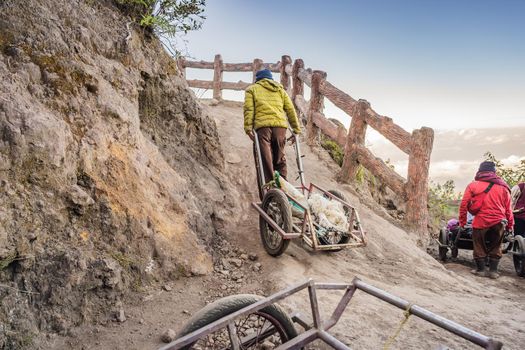 On a mountain road trecking to the Ijen volcano or Kawah Ijen on the Indonesian language. Famous volcano containing the biggest in the world acid lake and sulfur mining spot at the place where volcanic gasses come from the volcano. Local people use this trolleys to bring tired tourists up to the volcano or bring them back down.