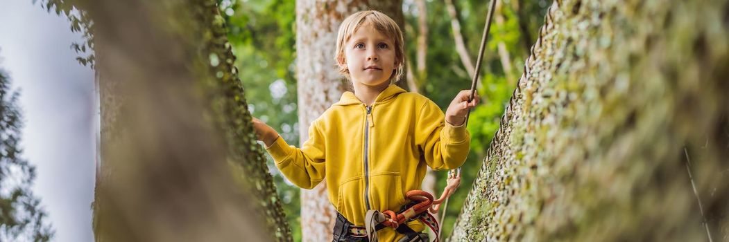 Little boy in a rope park. Active physical recreation of the child in the fresh air in the park. Training for children. BANNER, LONG FORMAT