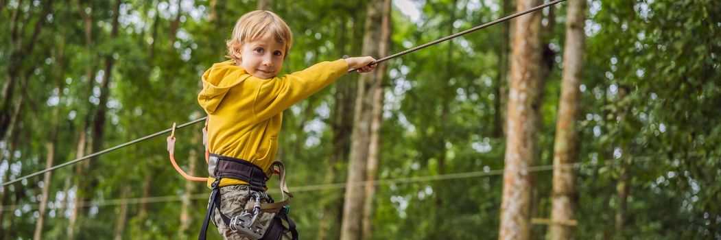 Little boy in a rope park. Active physical recreation of the child in the fresh air in the park. Training for children. BANNER, LONG FORMAT