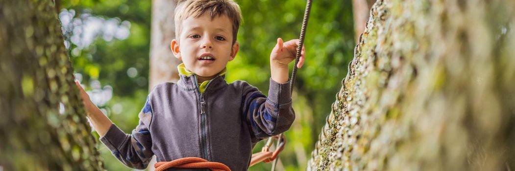 Little boy in a rope park. Active physical recreation of the child in the fresh air in the park. Training for children. BANNER, LONG FORMAT