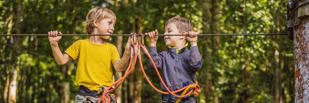 Two little boys in a rope park. Active physical recreation of the child in the fresh air in the park. Training for children. BANNER, LONG FORMAT