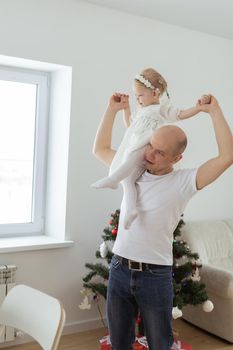 Baby child with hearing aid and cochlear implant having fun with father on christmas tree background. Deaf , diversity and health