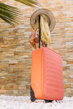 luggage in front of a stone wall and grass floor to use text. suitcase with hat and sunglasses. graphic resource. copy space. Vertical.