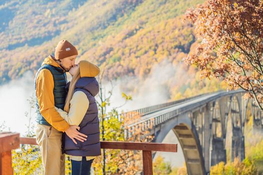 Montenegro. Happy couple man and woman in background of Dzhurdzhevich Bridge Over The River Tara foggy morning. Travel around Montenegro concept. Sights of Montenegro.