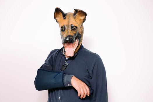 person with a dog mask and arm in a sling due to injury on white background, concept of veterinary care for pets