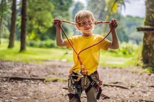 Little boy in a rope park. Active physical recreation of the child in the fresh air in the park. Training for children.