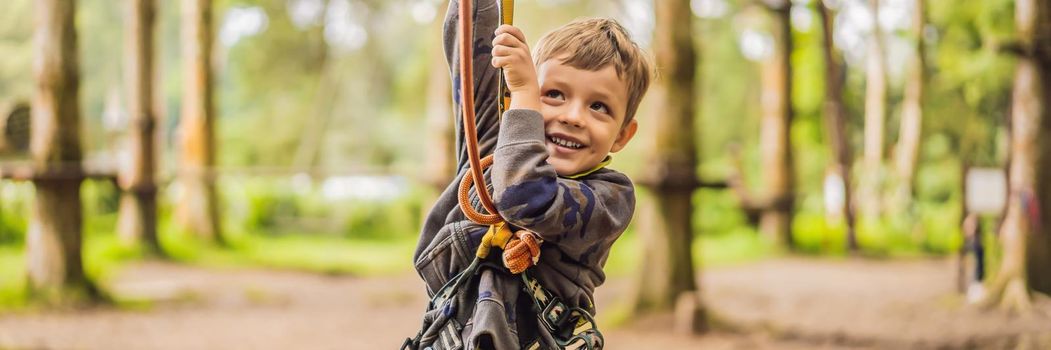 Little boy in a rope park. Active physical recreation of the child in the fresh air in the park. Training for children. BANNER, LONG FORMAT