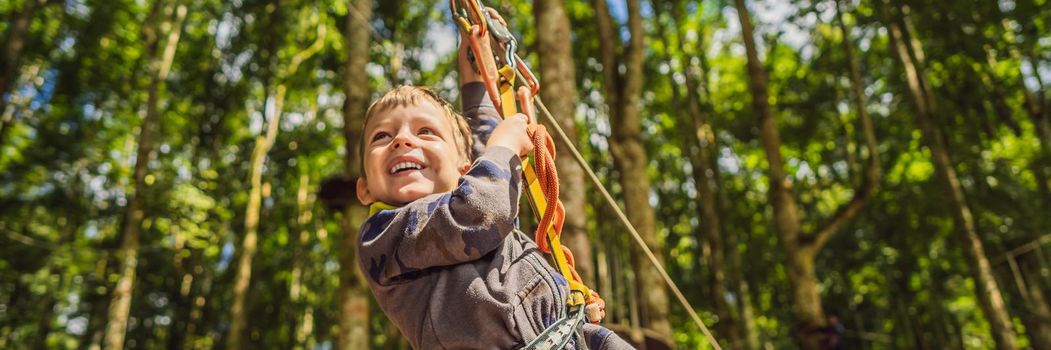 Little boy in a rope park. Active physical recreation of the child in the fresh air in the park. Training for children. BANNER, LONG FORMAT