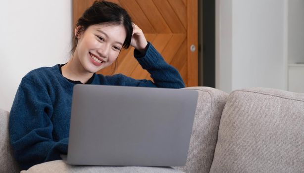 Asian Girl Working on Laptop Online, Using Internet, Sitting on Sofa at Home, Free Space.