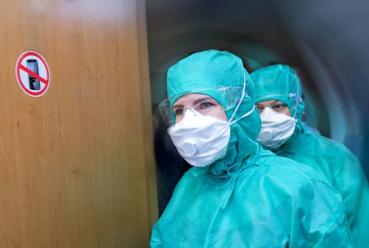A woman in a hygiene mask and gloves is trying to avoid the coronavirus epidemic. Transportation of the patient in a protective box.