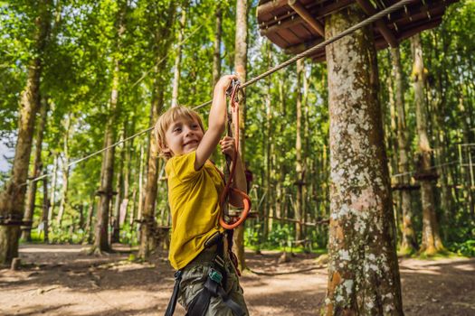 Little boy in a rope park. Active physical recreation of the child in the fresh air in the park. Training for children.