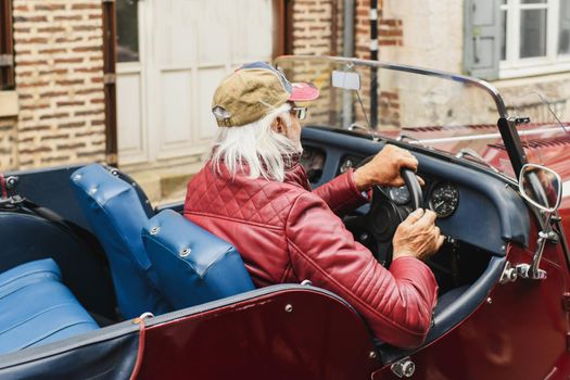 Grey-haired grandfather drives a vintage car