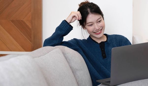 Asian Girl Working on Laptop Online, Using Internet, Sitting on Sofa at Home, Free Space.