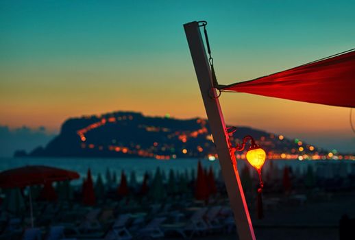 Lantern on the beach at sunset with Alanya peninsula