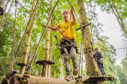 Little boy in a rope park. Active physical recreation of the child in the fresh air in the park. Training for children.