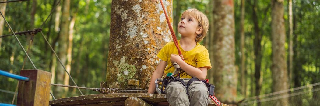 Little boy in a rope park. Active physical recreation of the child in the fresh air in the park. Training for children. BANNER, LONG FORMAT