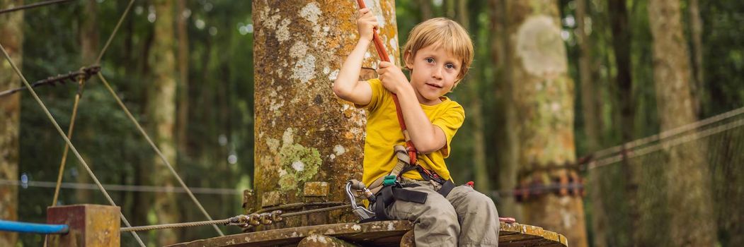 Little boy in a rope park. Active physical recreation of the child in the fresh air in the park. Training for children. BANNER, LONG FORMAT