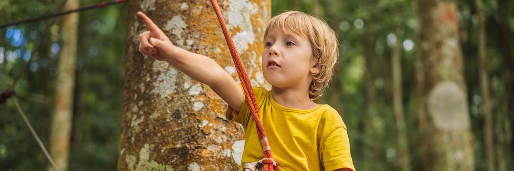 Little boy in a rope park. Active physical recreation of the child in the fresh air in the park. Training for children. BANNER, LONG FORMAT