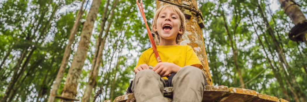 Little boy in a rope park. Active physical recreation of the child in the fresh air in the park. Training for children. BANNER, LONG FORMAT