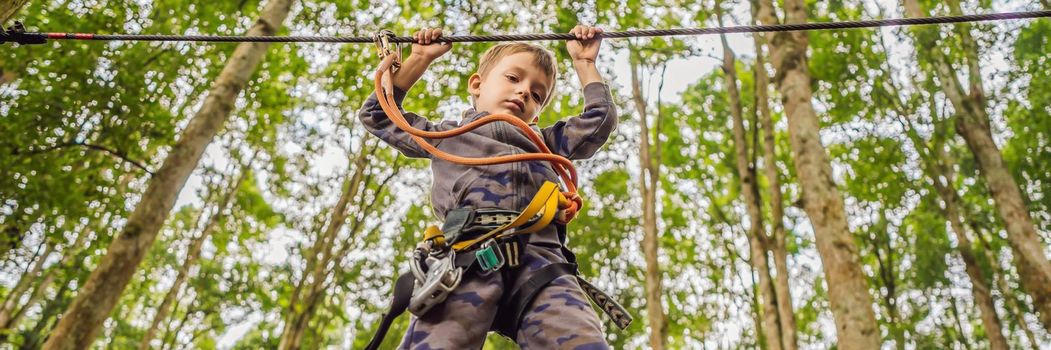 Little boy in a rope park. Active physical recreation of the child in the fresh air in the park. Training for children. BANNER, LONG FORMAT