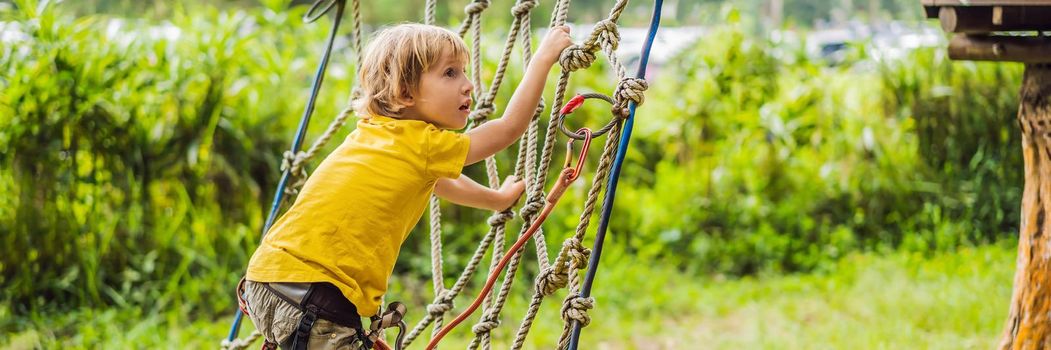 Little boy in a rope park. Active physical recreation of the child in the fresh air in the park. Training for children. BANNER, LONG FORMAT