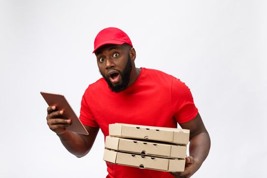 Delivery Concept: Handsome african pizza delivery man talking to mobile with shocking facial expression. Isolated over grey background