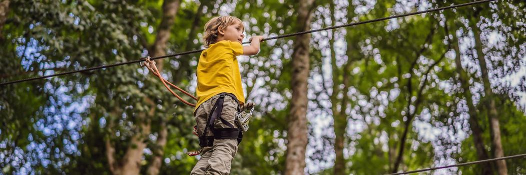 Little boy in a rope park. Active physical recreation of the child in the fresh air in the park. Training for children. BANNER, LONG FORMAT