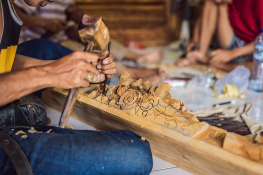 Master wood-carver made using a special knife wooden national dish - a ladle with a patterned handle. A fragment of a close-up of his hands.