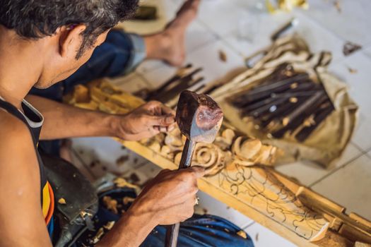 Master wood-carver made using a special knife wooden national dish - a ladle with a patterned handle. A fragment of a close-up of his hands.