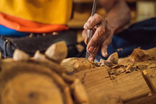 Master wood-carver made using a special knife wooden national dish - a ladle with a patterned handle. A fragment of a close-up of his hands.