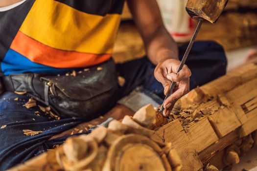 Master wood-carver made using a special knife wooden national dish - a ladle with a patterned handle. A fragment of a close-up of his hands.