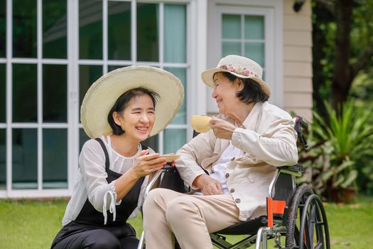 Elderly woman relax on wheelchair in backyard with daughter