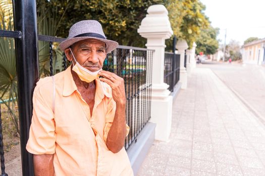 Latino elderly man with a hat and no beard in taking off his medical mask in the street of Ocotal Nueva Segovia, Nicaragua.