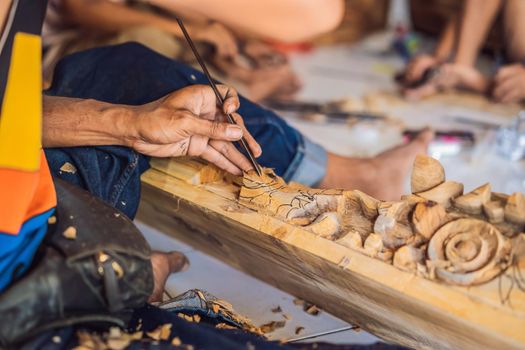 Master wood-carver made using a special knife wooden national dish - a ladle with a patterned handle. A fragment of a close-up of his hands.