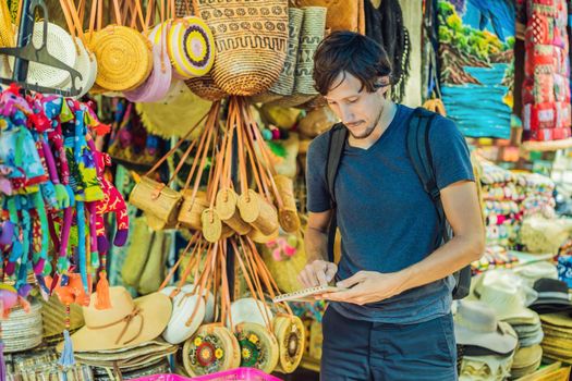 Man at a market in Ubud, Bali. Typical souvenir shop selling souvenirs and handicrafts of Bali at the famous Ubud Market, Indonesia. Balinese market. Souvenirs of wood and crafts of local residents.