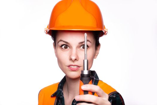 a woman in a construction helmet, and an orange vest holds a construction tool in her hand, white studio background, close-up portrait. High quality photo