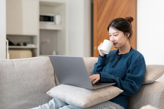 Image of young asian cheery happy positive cute beautiful business woman sit indoors in office using laptop computer.
